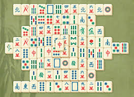 Tuiles de Mahjong traditionnelles gravées avec des caractères chinois, des bambous et des dragons, disposées sur une table de jeu.